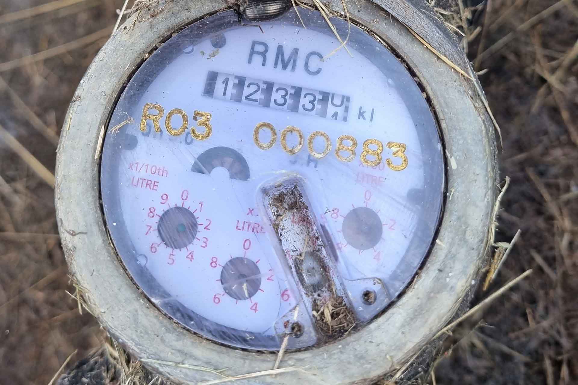Close up of water meter showing numbers on dial.