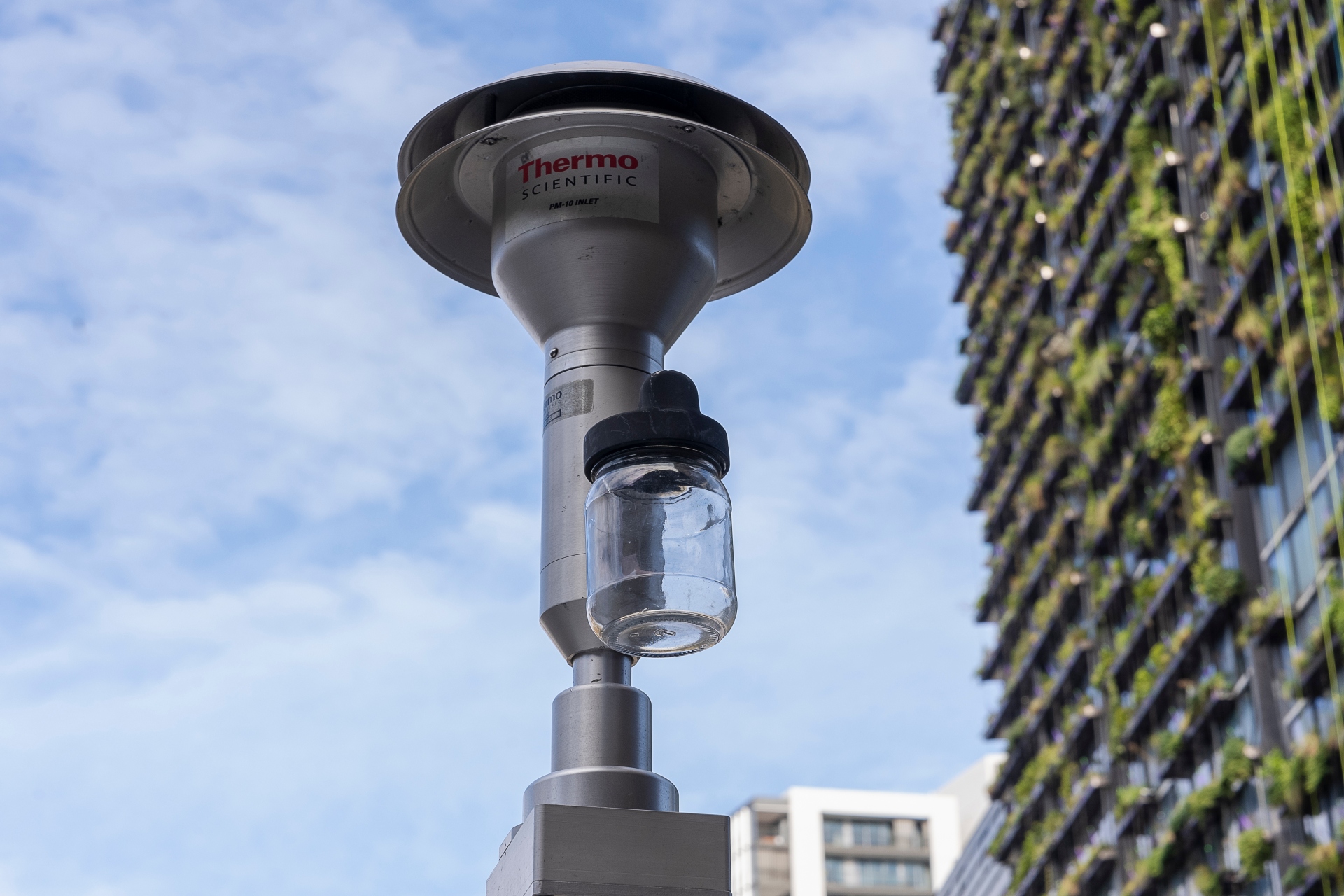 Air quality monitoring equipment, with a high-rise building and blue sky in the background
