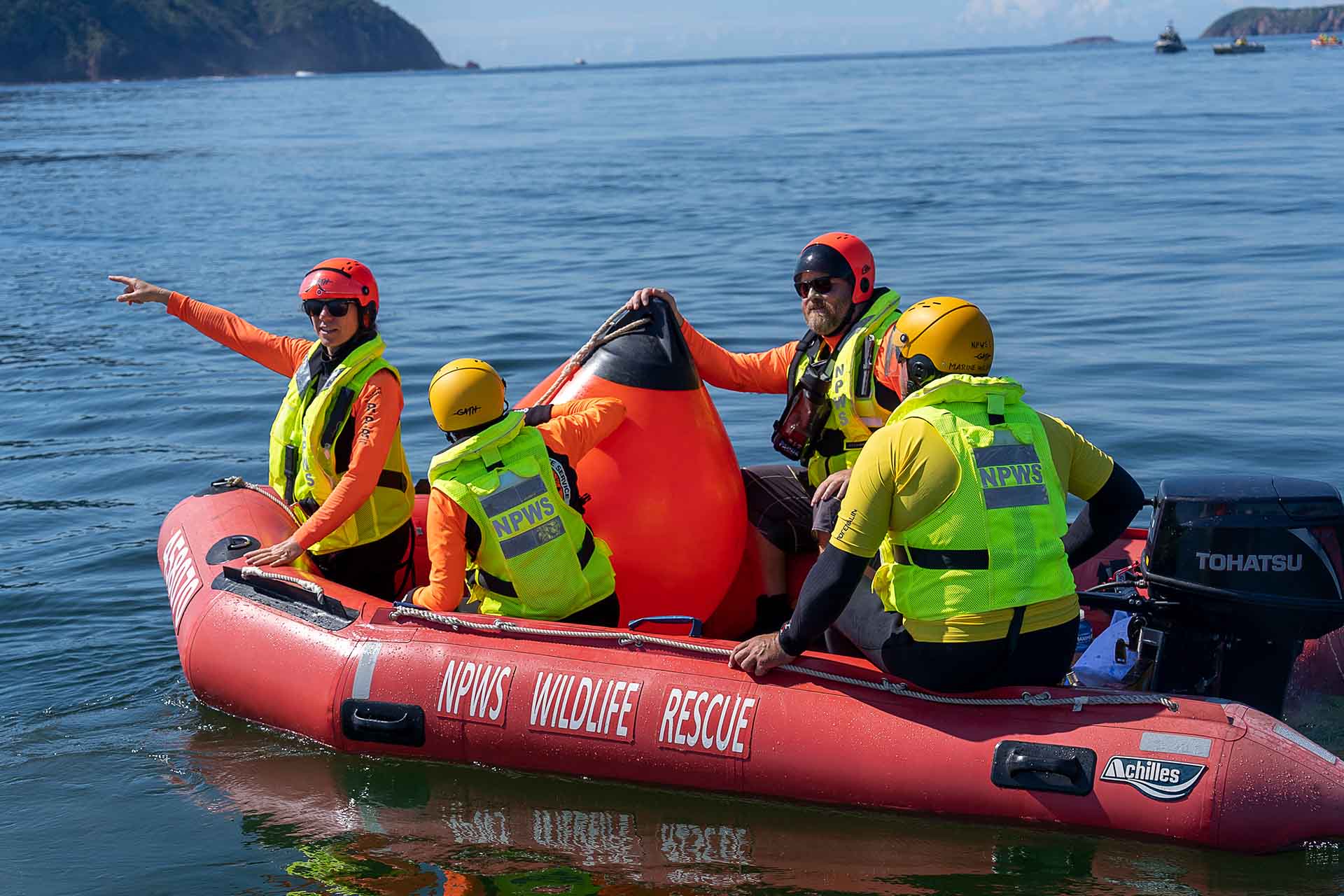 Several NPWS staff in yellow vests with a large buoy in a rubber boat.
