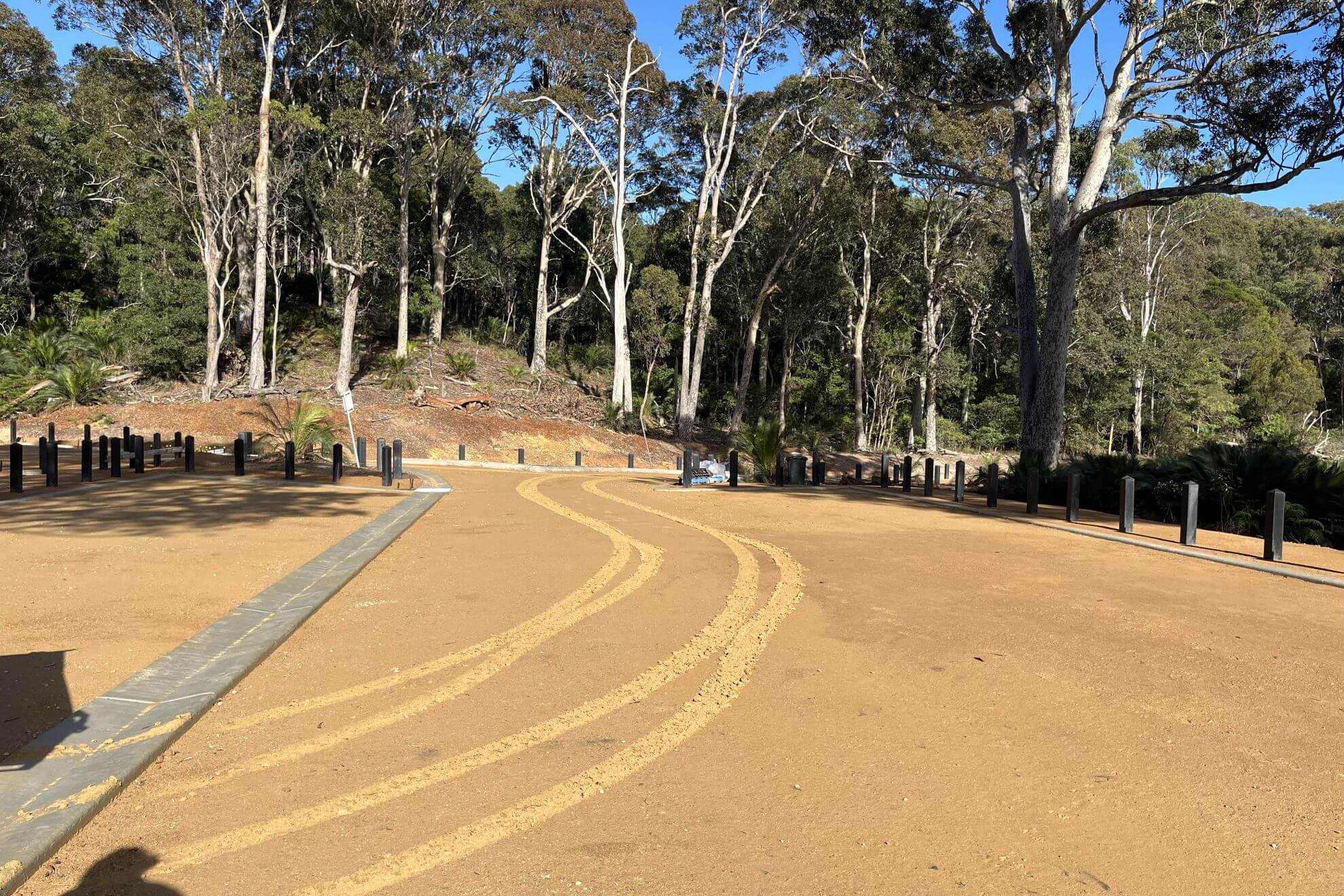 Red dirt graded road with trees in background