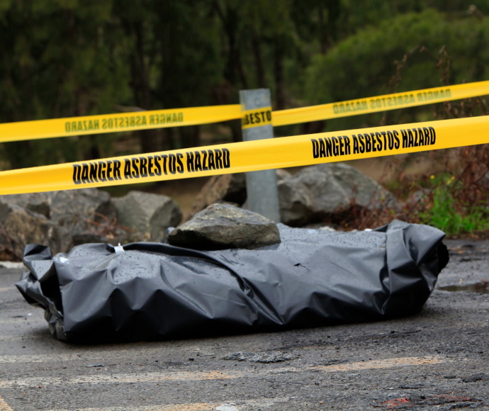 Illegally dumped asbestos wrapped in heavy black plastic and surrounded by yellow hazard tape