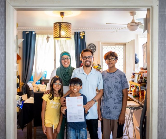 Smiling parents and 3 children posing together in portrait style.