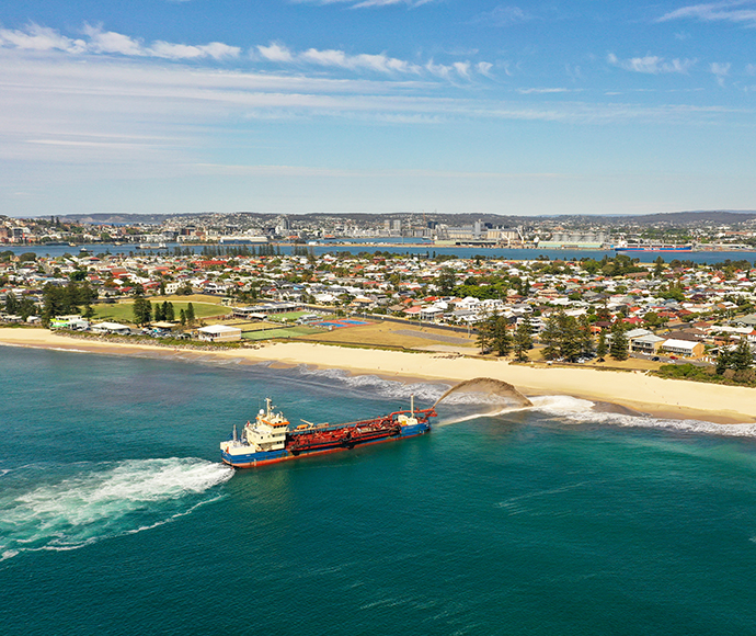Large boat streaming sand onto beach.